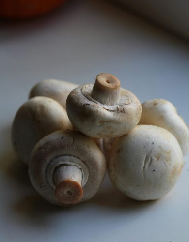 pexels photo 9944543 9944543 A stack of fresh white button mushrooms in natural lighting indoors, ideal for culinary and healthy eating themes.